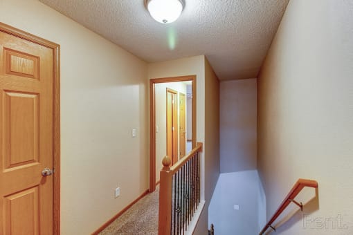 the upstairs landing of a house with a staircase and a door to a hallway with