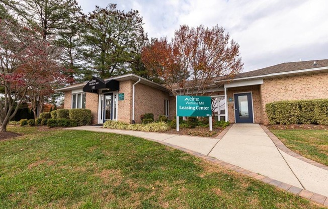 A leasing center is located in a building with a brick exterior and a green lawn in front.