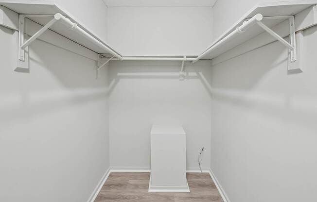 A white walk-in closet with a white pedestal in the middle.