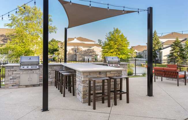 a patio with a grill and a bar with stools