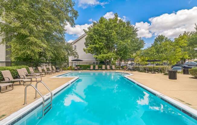 a swimming pool with chairs and trees and a building in the background at Sanger Place, Virginia, 22079