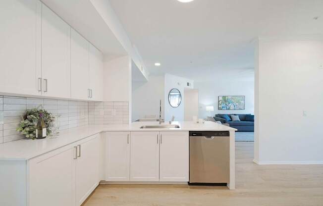 A kitchen with white cabinets and a trash can.