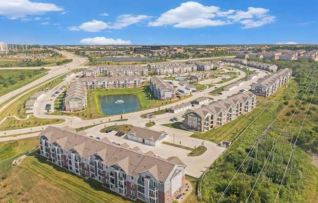 A large residential complex with multiple buildings and a central pond at Strathmore Apartment Homes, West Des Moines, IA