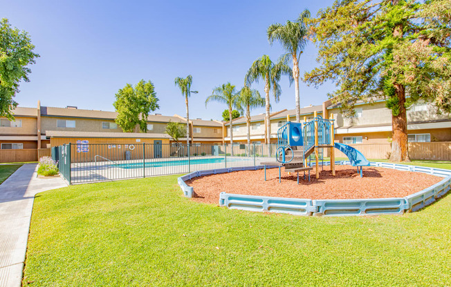 a playground with a blue playset in the grass