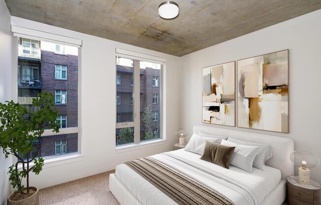 A flexible bedroom with concrete ceilings, soft carpeting, and natural light, offering a versatile space that adapts to work, rest, or creativity.