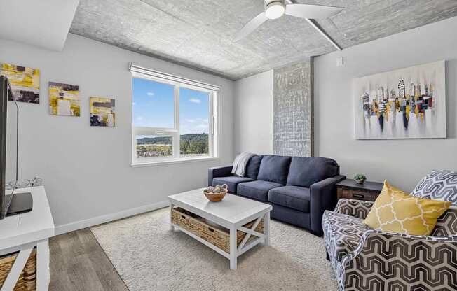 A living room with a grey sofa, a white coffee table, and a painting on the wall.
