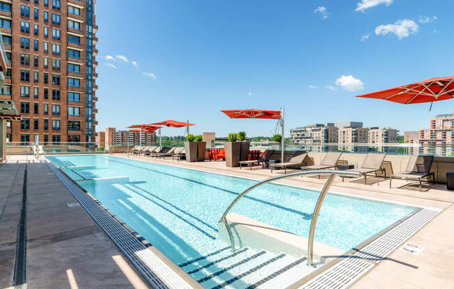 a swimming pool with chairs and umbrellas on a sunny day at a hotel