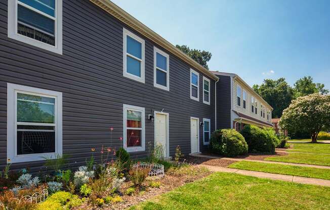 A grey building with white windows and a green lawn in front.