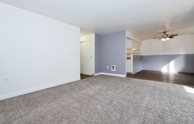 an empty living room with a ceiling fan