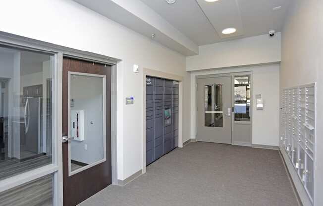 A hallway with a white wall and a brown door. Fargo, ND 29 West Apartments