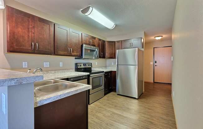 a kitchen with stainless steel appliances and wooden cabinets. Fargo, ND Urban Plains Apartments