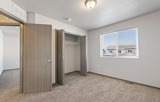 Bright, vacant bedroom with neutral walls and carpet flooring.