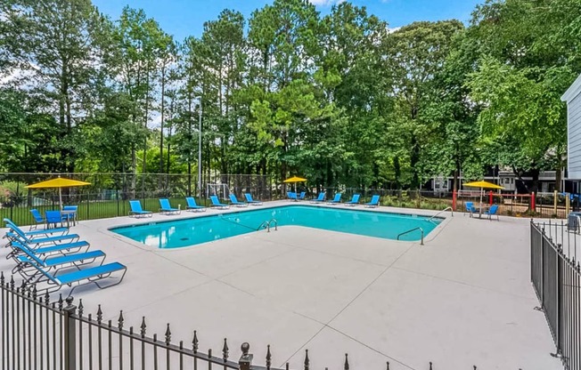 a swimming pool with chaise lounge chairs and trees in the background