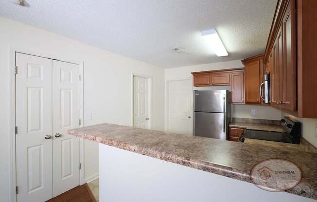 A kitchen with a vinyl flooring, dark cabinets, a pantry, bathroom, and laundry room.