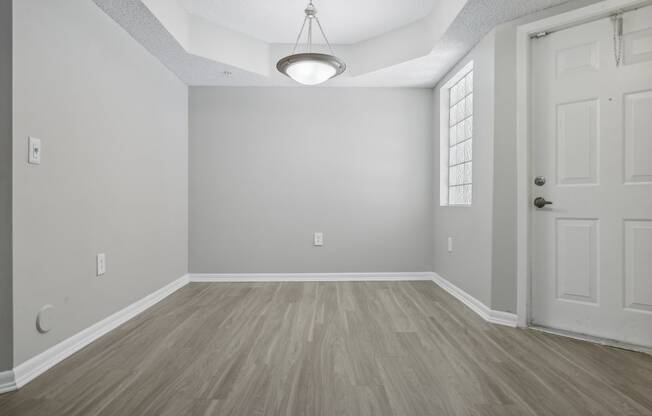 an empty living room with a white door and wood flooring at Pembroke Pines Landings, Florida, 33025