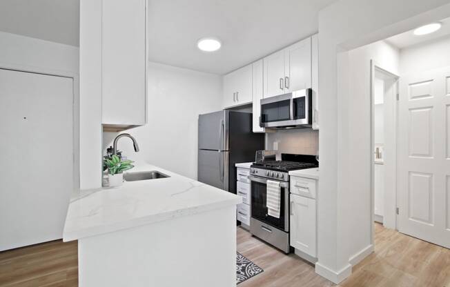 A kitchen with white cabinetry and stainless steel appliances at Harvard Manor, Irvine, 92612