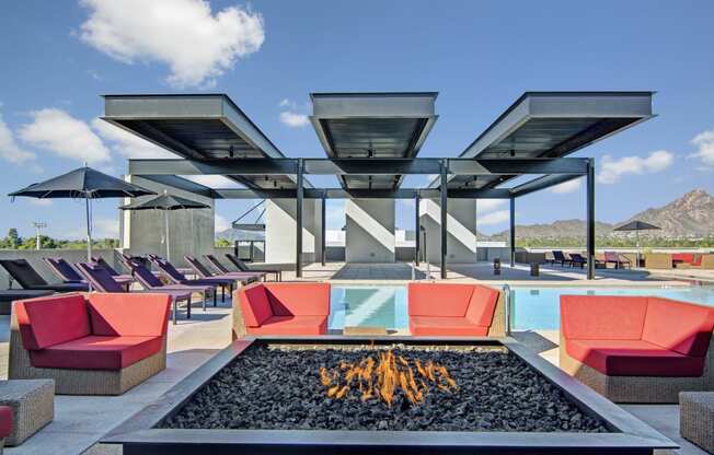 a lounge area with couches and chairs around a fire pit
