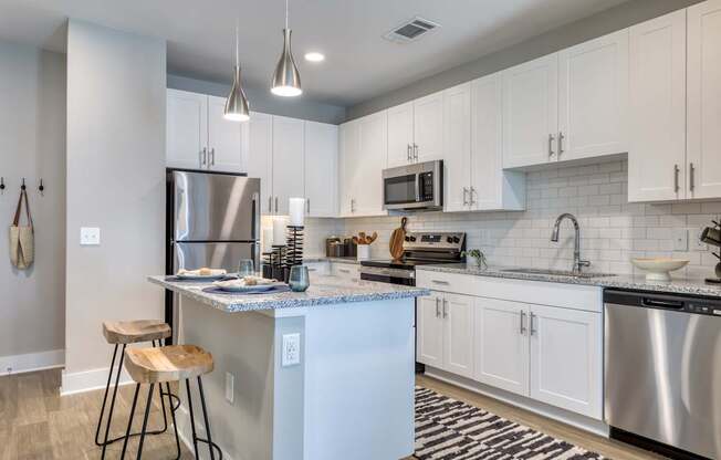 A kitchen with a white island and stainless steel appliances.