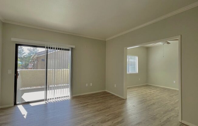 an empty living room with a sliding glass door to a balcony