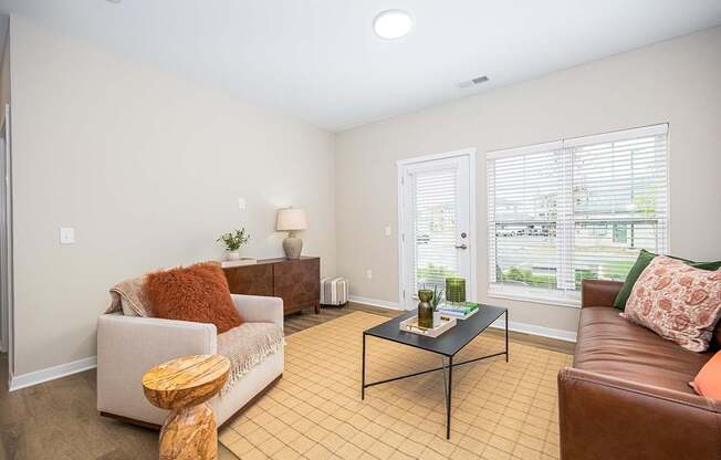 A living room with a brown leather couch, a white sofa, and a wooden coffee table.