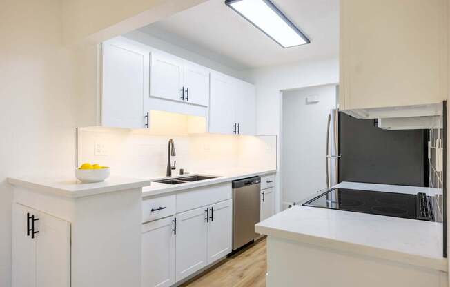 A kitchen with white cabinets and a black fridge.