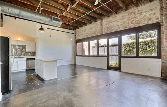 an empty room with a kitchen and a large window