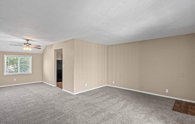 an empty living room with carpet and a ceiling fan