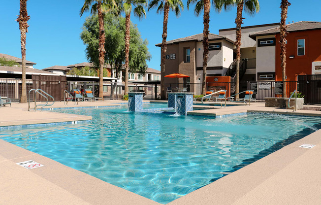 A pool surrounded by palm trees and apartment buildings.