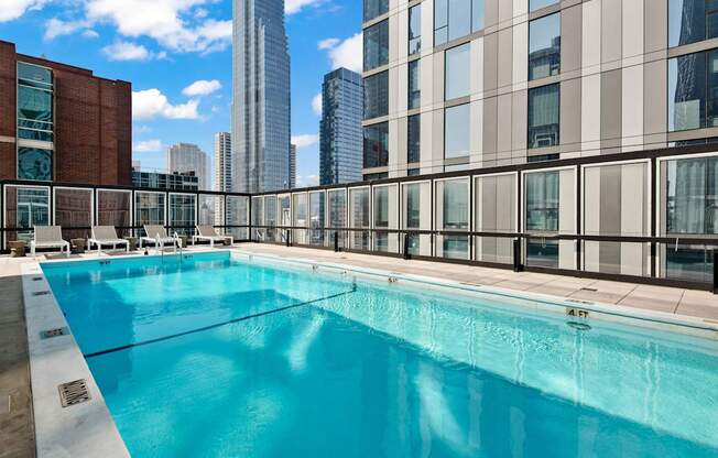 A large swimming pool on a rooftop with a city skyline in the background.