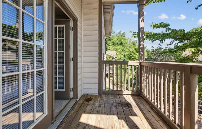 A wooden deck with a sliding glass door leading to a patio.