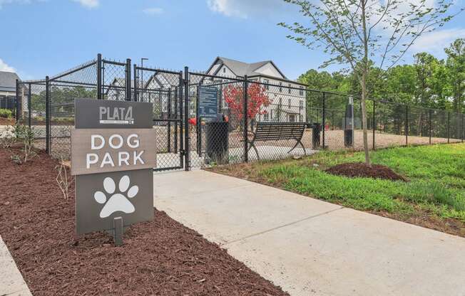a dog park sign in front of a fenced in dog park