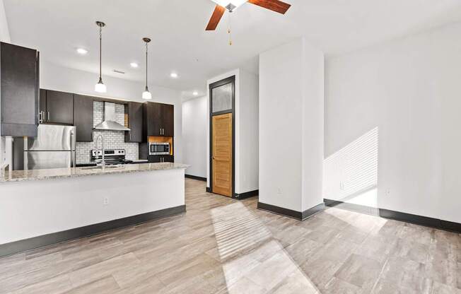 A modern kitchen with a wooden floor and white walls.