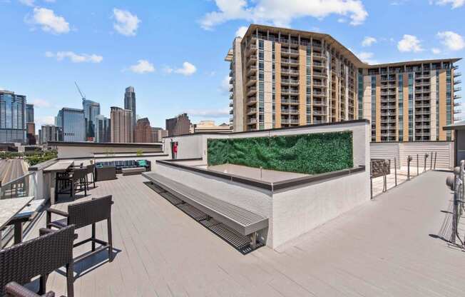 a rooftop terrace with a green wall and benches and a view of the city