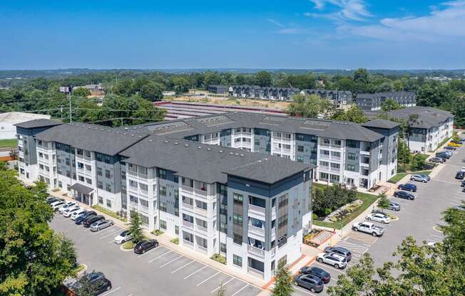 an aerial view of a large apartment complex with a parking lot and trees