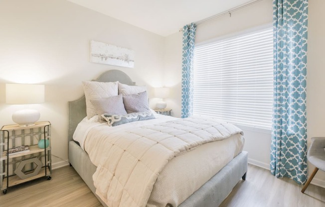 a bedroom with a bed and a window with blue curtains