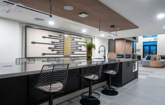 A modern kitchen with a bar area featuring a black counter and three barstools.