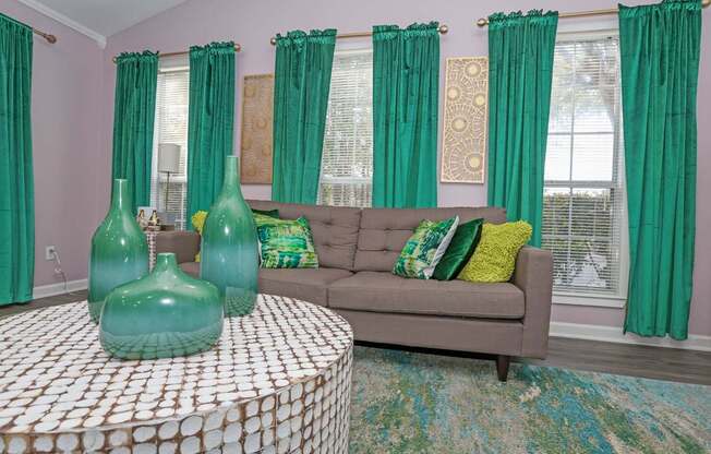 A clubhouse with a grey couch and green curtains at The Marq in Shreveport, LA