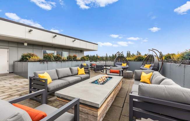 A patio with grey couches and orange pillows.