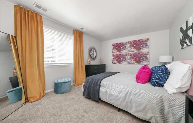 a bedroom with a bed and a window with orange curtains