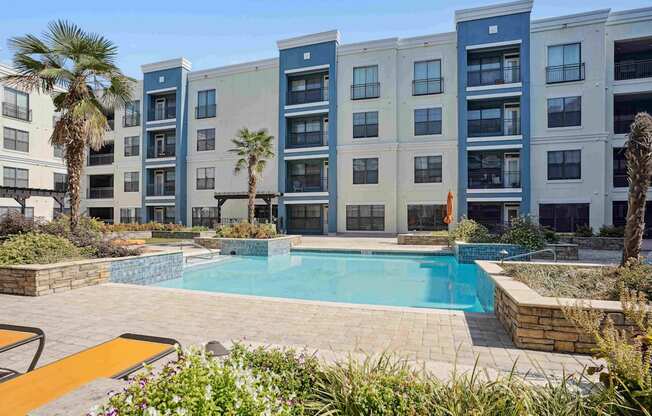 A pool surrounded by a patio and a building.