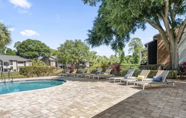 a swimming pool with chaise lounge chairs next to a house