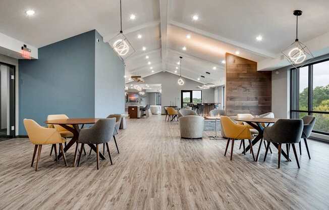 a dining room with tables and chairs and a large window. Circle Pines, MN Lexington Lofts