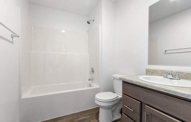 A white toilet sits next to a white bathtub in a bathroom.