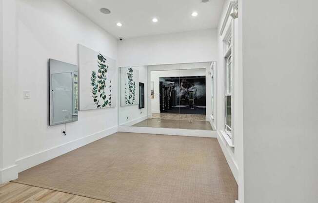 A hallway with a carpeted floor and a mirror on the wall.