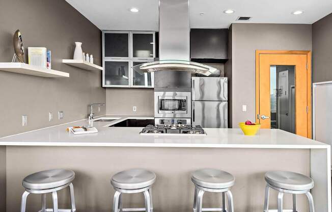 A modern kitchen with a white countertop and stainless steel appliances.