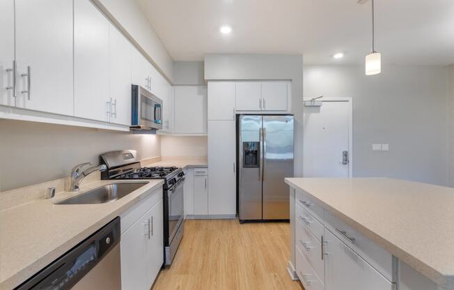 a kitchen with white cabinets and a stainless steel refrigerator at Metro Gateway, California
