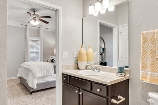 A bathroom with a white ceiling fan, a white sink, and a white bed.