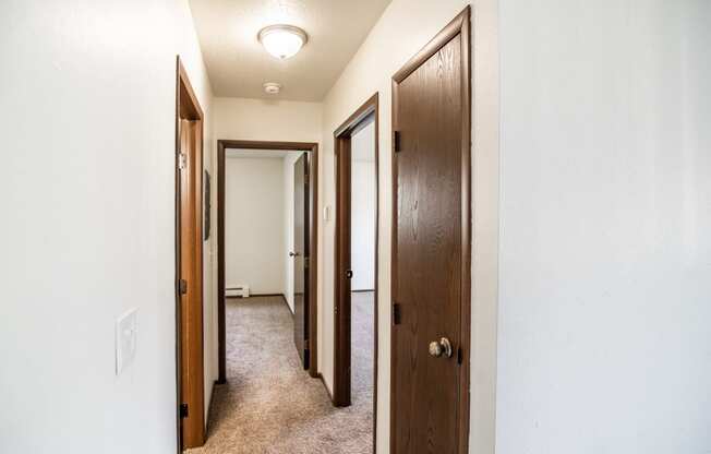 Bismarck, ND Rosser Apartments. a corridor with three doors and a carpeted floor