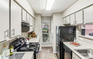 Model apartment kitchen with black appliances at Hunters Chase in Austin, TX