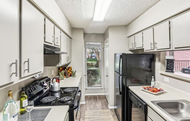 Model apartment kitchen with black appliances at Hunters Chase in Austin, TX